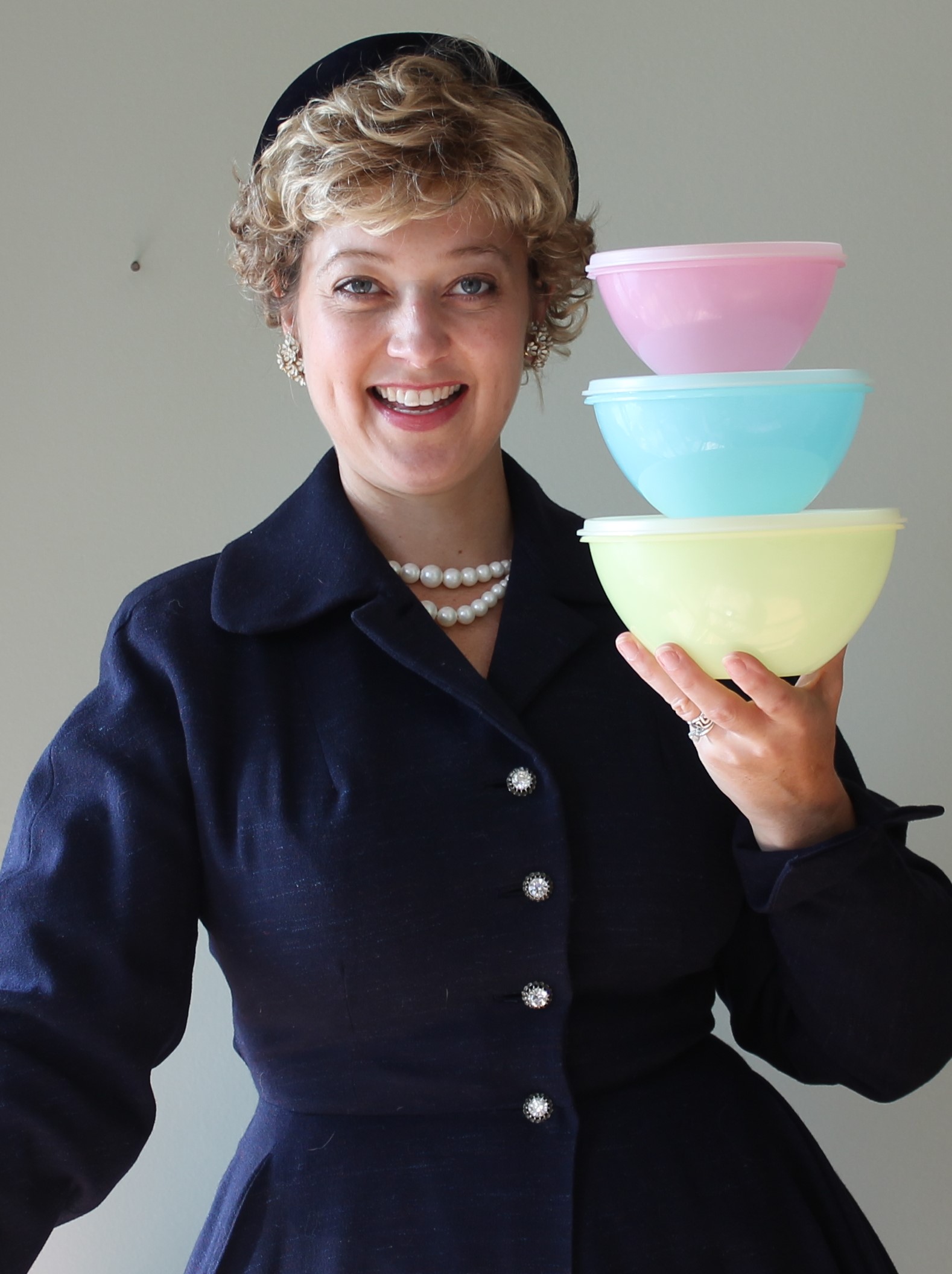 Picture of Leslie Goddard in character as Brownie Wise holding three Tupperware containers