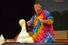 Man with tie-dye shirt on and a beaker with elephant toothpaste exploding
