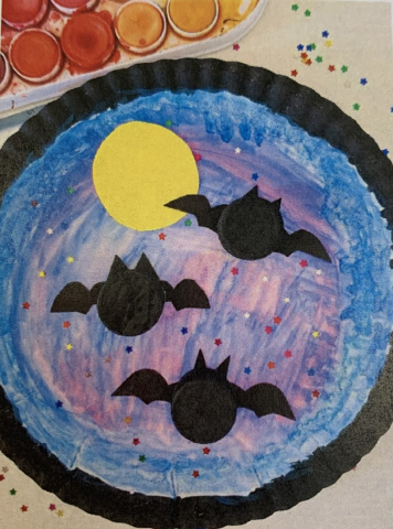 bats made of bottle caps on a paper plate painted to look like the night sky with a full moon