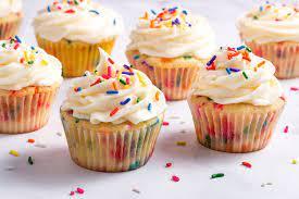 cupcakes with vanilla icing and rainbow sprinkles