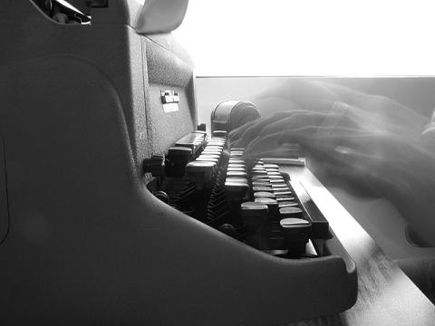 Black and white image of a typewriter in profile with hands flying across it.