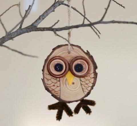 Flat circular wooden owl hanging on a tree branch