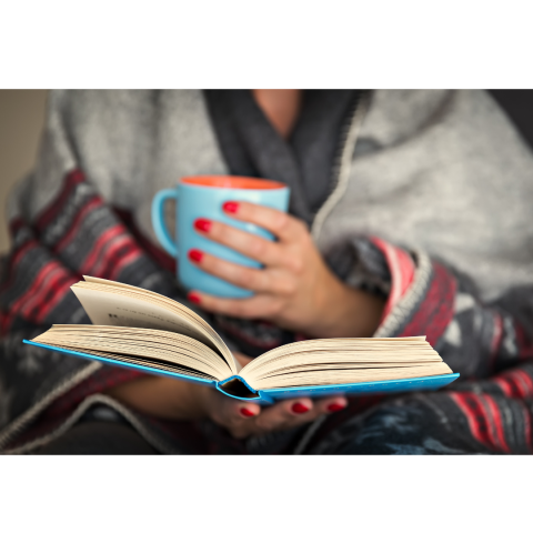 woman's torso holding a mug and a book