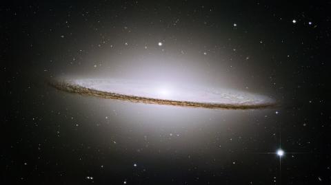 Color Image of the Sombrero Galaxy with light emitting from the top and bottom of the galaxy making a sombrero shape