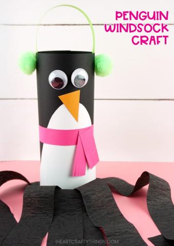 penguin paper towel roll with green earmuffs, pink scarf, and black streamers