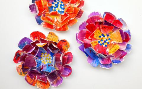 three paper plate flowers painted in bright colors