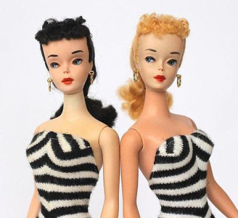 Two Barbie dolls in black and white striped bathing suits