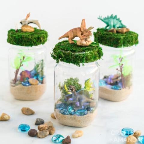 dinoaurs, rocks, and sand inside jars