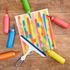 bottles of paint, a squeegee, and some art on a canvas