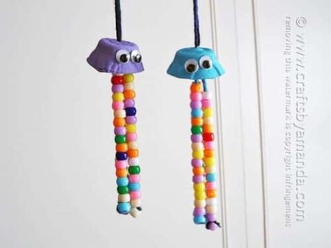 two hanging egg carton cups with strings of beads hanging down like jellyfish with tentacles