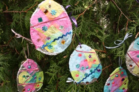 egg shapes of tin foil decorated with tissue paper, beads, and ribbon